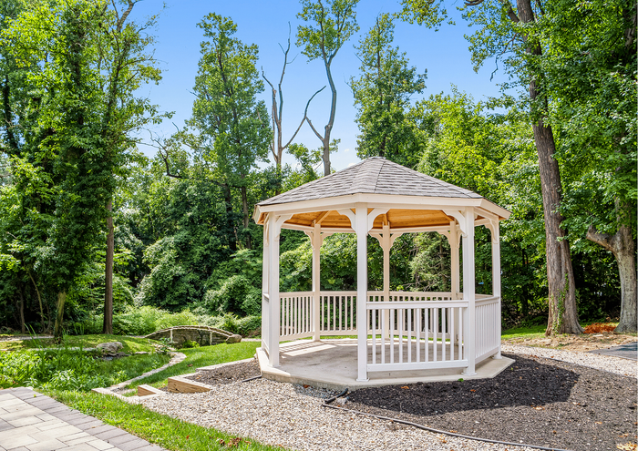 Beautiful wooden gazebo surrounded by lush greenery and a small stone path.