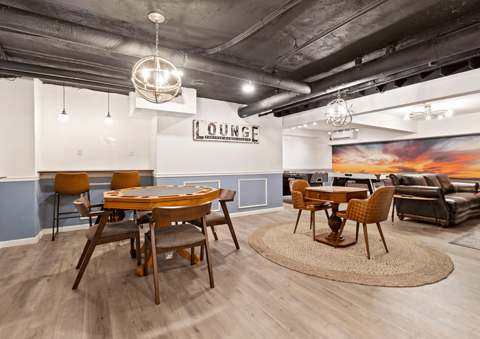 Stylish lounge area with game table, comfortable seating, and modern lighting fixtures.