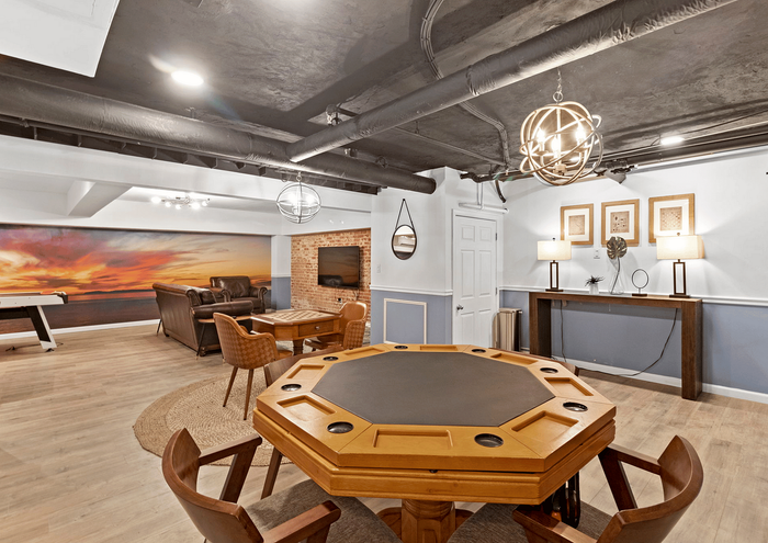 Elegant basement lounge with a poker table, leather seating, and vibrant mural decor.
