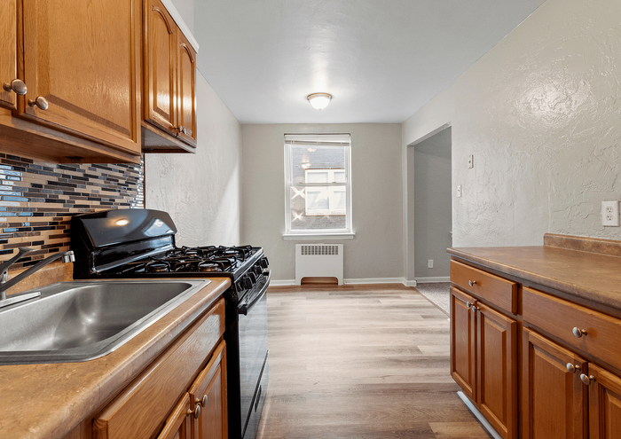 Bright and inviting kitchen with wooden cabinetry, modern gas stove, and mosaic backsplash.