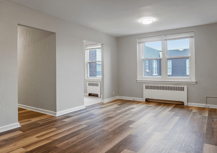 Bright and spacious apartment room with large windows and hardwood flooring.