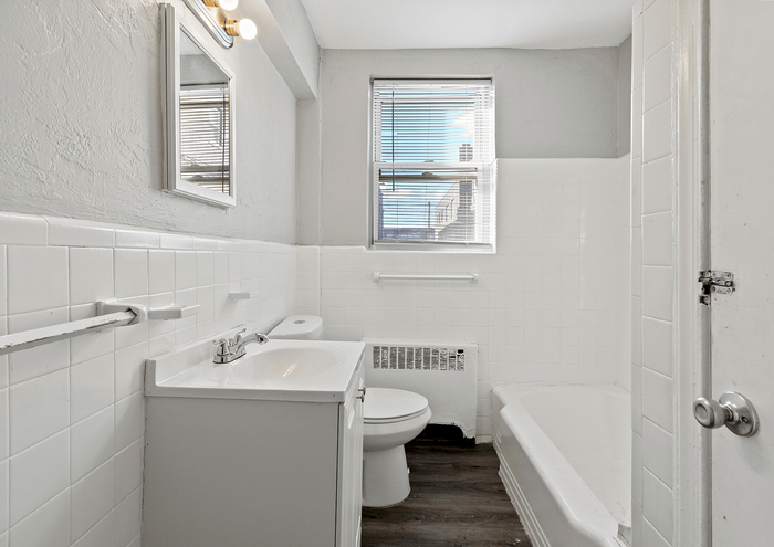 Contemporary bathroom with white tiles, sleek vanity, and sunlight through the window.