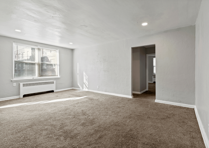 Bright and airy living room with large windows and plush carpeting.