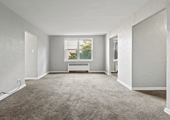 Bright living room with neutral tones, large window, and plush carpet.