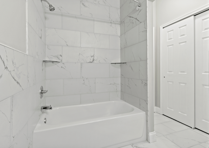 Sleek and modern bathroom featuring a pristine white bathtub and elegant marble wall tiles.