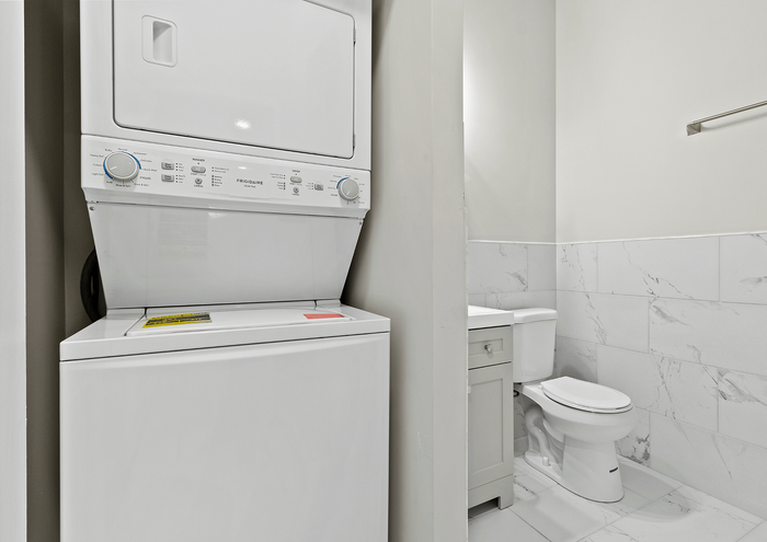 Efficient laundry area with stackable washer and dryer next to a modern powder room.