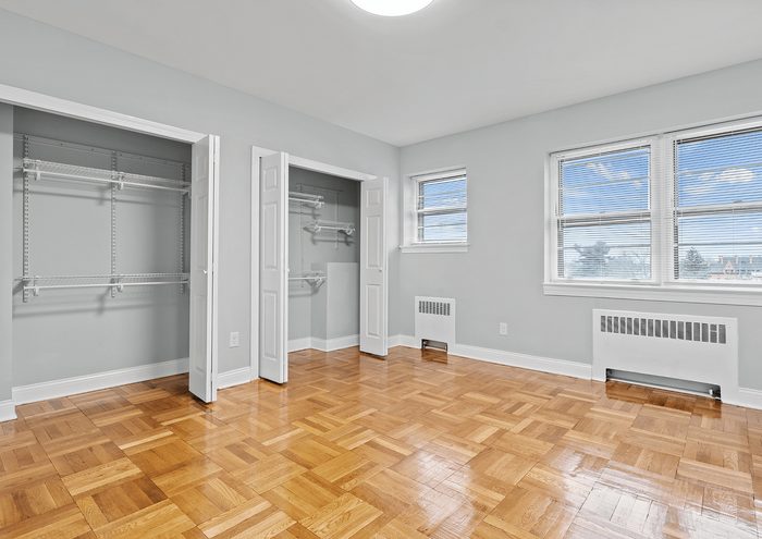 Bright, spacious bedroom with parquet flooring and large closets offers ample storage.