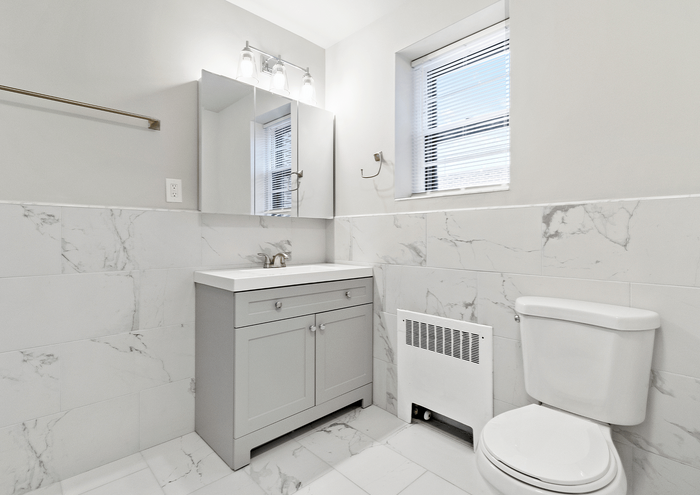 Bright bathroom with marble tiles, modern vanity, and window lighting.