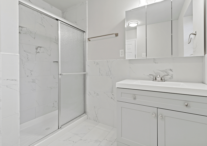 Modern bathroom with sleek marble tiles and a glass shower door.