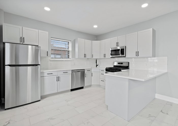 Bright and modern kitchen with stainless steel appliances, white cabinetry, and marble flooring.