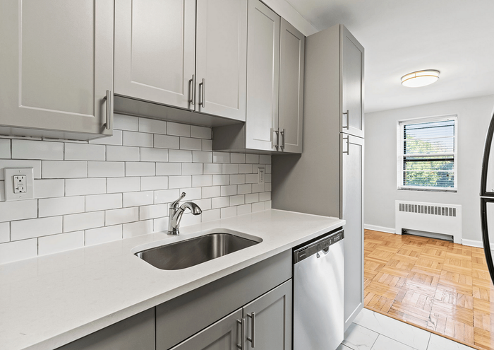 Modern kitchen with sleek cabinetry, stainless steel appliances, and a pristine white tile backsplash.