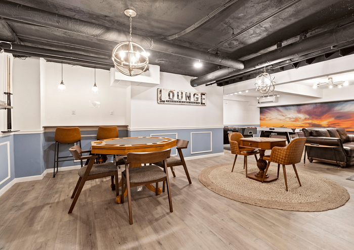 Cozy lounge area with stylish furniture, featuring a poker table and plush seating under modern lighting.