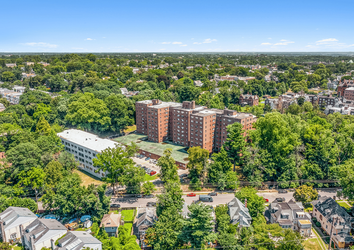 Aerial view of a stylish apartment complex nestled in lush greenery with nearby residential homes.