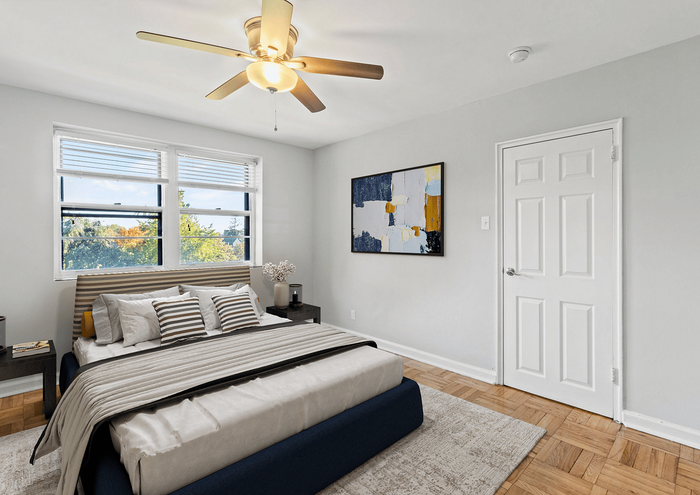 Bright and inviting bedroom with modern decor, large windows, and a ceiling fan.