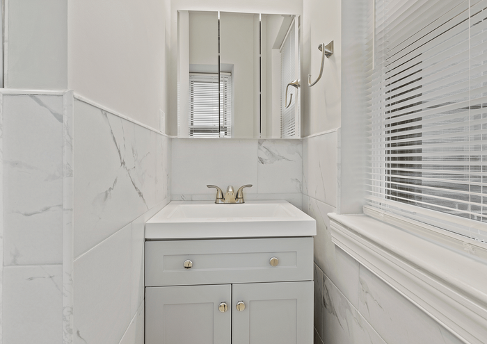 Bright and modern bathroom with a sleek vanity and marble tile accents.