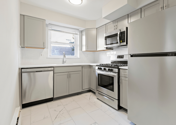 Modern kitchen with stainless steel appliances, gray cabinets, and white tile backsplash.