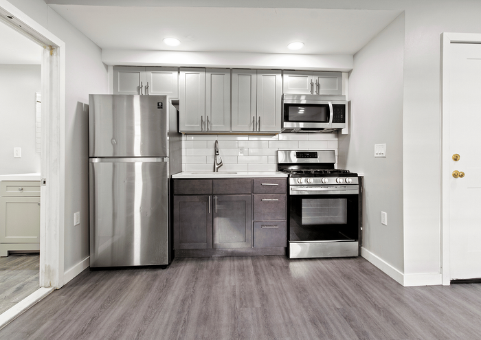 Contemporary kitchen with stainless steel appliances, gray cabinets, and clean white backsplash.