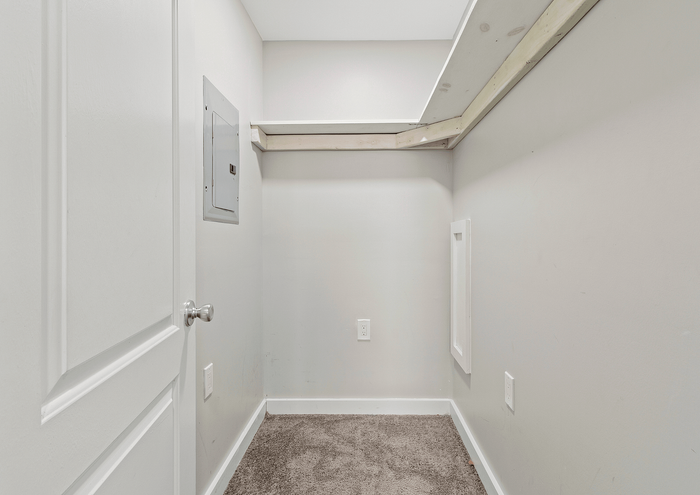 Compact storage space with carpeted flooring and built-in shelving.