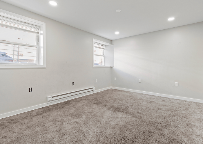 Well-lit empty room with carpeted floor and large windows, ideal for flexible design.