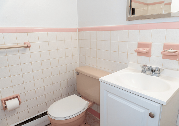 Cozy bathroom with retro pink and white tile design, featuring a classic sink and toilet setup.