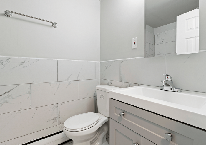 Modern bathroom with sleek white marble tiles, stylish vanity, and chrome fixtures.