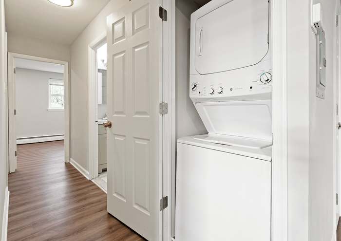 Bright hallway showcasing an efficient in-unit washer and dryer with laminate flooring.