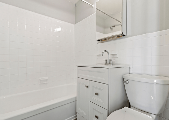 Modern white bathroom with subway tile walls, a bathtub, and a sleek vanity.