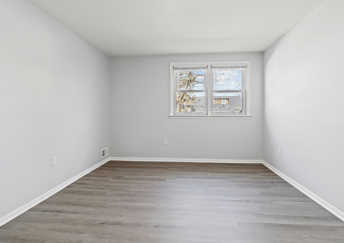 Spacious room with large window and elegant hardwood flooring.
