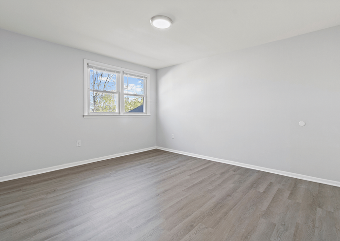 Spacious room with modern gray laminate flooring and large window offering natural light.