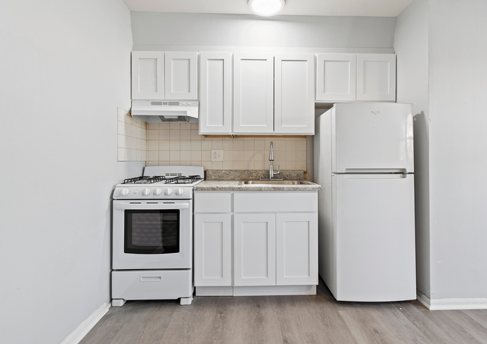 Compact modern kitchen with white cabinets, gas stove, and fridge.