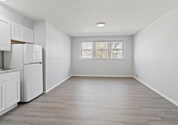 Contemporary living room with large windows and open layout, featuring sleek floors and modern kitchen cabinets.
