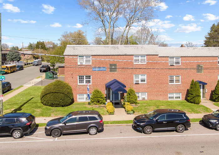 Red brick apartment building with lush greenery and convenient parking in a serene neighborhood.
