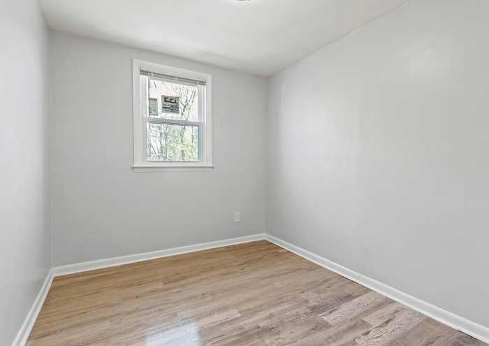 Bright and spacious room with elegant wood flooring and a large window for natural light.