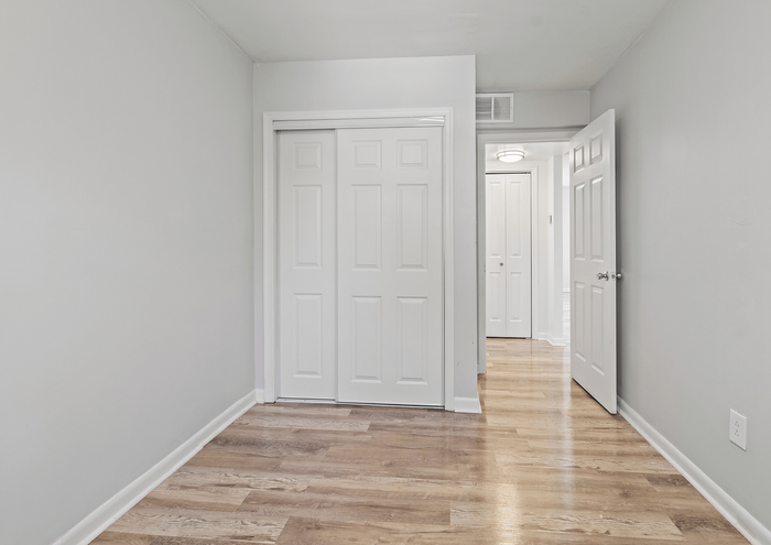 Inviting hallway with modern wooden flooring and white double doors leading to an adjacent room.