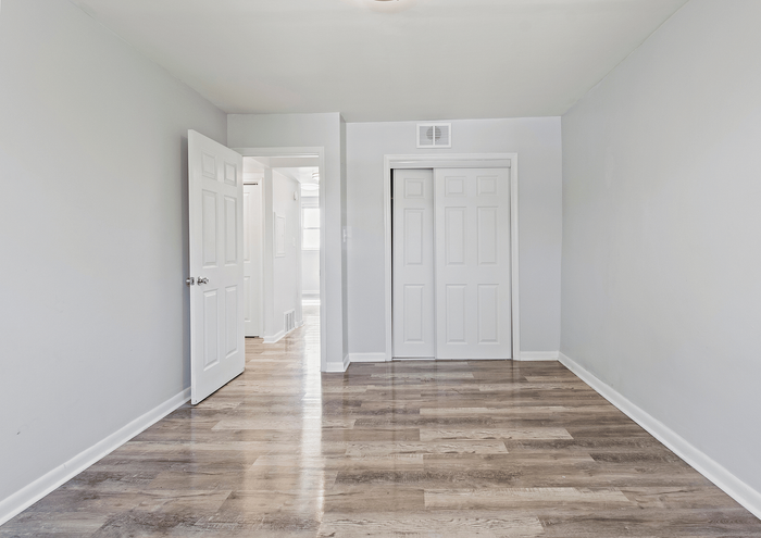 Bright room with sleek wood flooring and white closet doors.