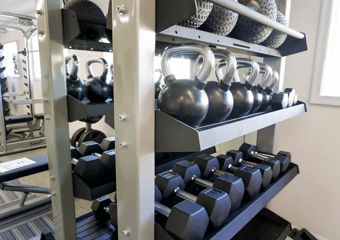 Modern fitness center with kettlebells and dumbbells on a sleek rack.