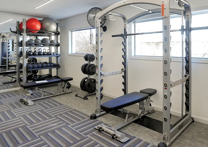 Modern gym interior with weight training equipment and bright natural lighting.