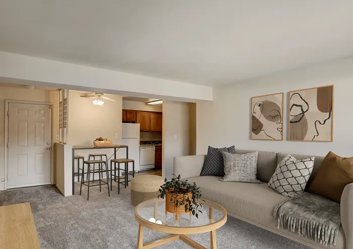 Inviting open-plan living room with contemporary decor, a comfortable sofa, modern art, and a compact kitchen area.