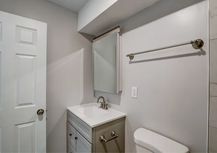 Modern bathroom with sleek white vanity, stylish fixtures, and minimalist aesthetic.