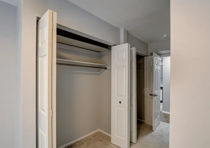 Elegant open closet with sleek sliding doors next to a bright hallway.