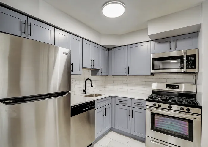 Contemporary kitchen with stainless steel appliances, gray cabinets, and white subway tile backsplash.