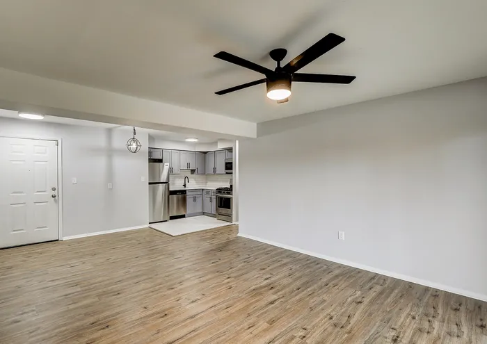 Bright open-concept living area with modern kitchen and sleek ceiling fan.
