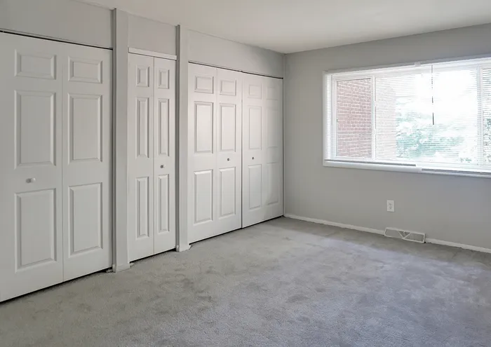 Sunlit bedroom with ample closet space and large window view.