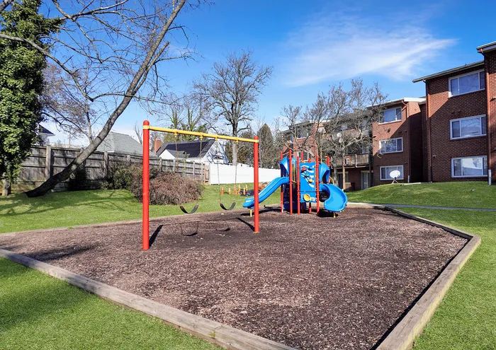 Inviting playground with slides and swings set against modern apartment buildings.