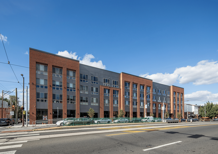 Modern brick and glass apartment building under a bright blue sky.