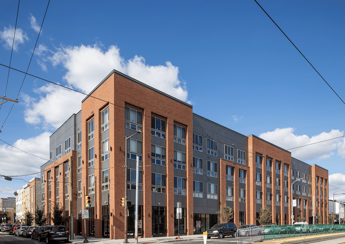 Contemporary apartment building with brick facade and large windows on a sunny day.