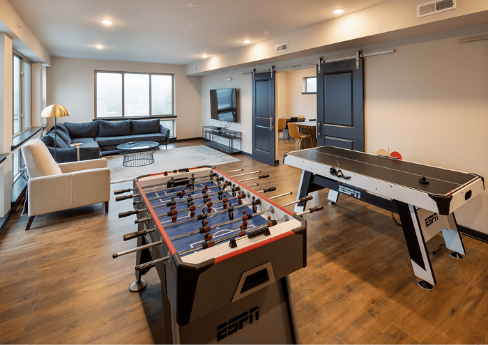 Stylish living area featuring foosball and air hockey tables, cozy seating, and modern decor.
