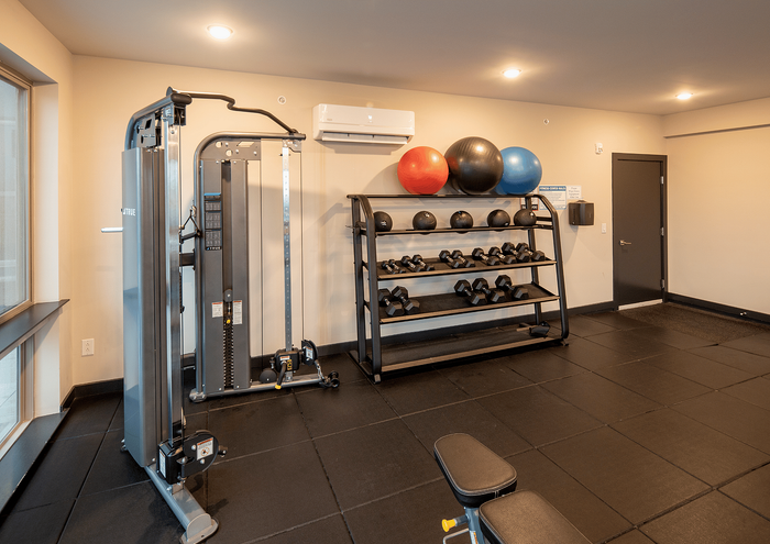 Well-equipped gym with weight rack, exercise balls, and workout bench in modern apartment complex.