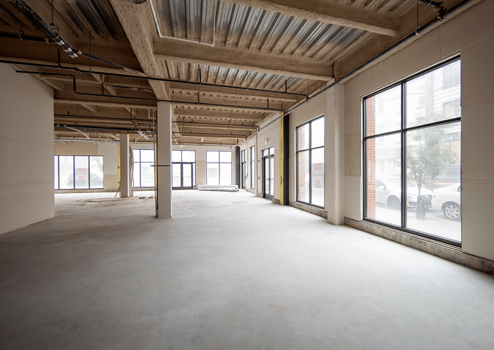 Bright open-plan commercial space with large windows and industrial ceilings.