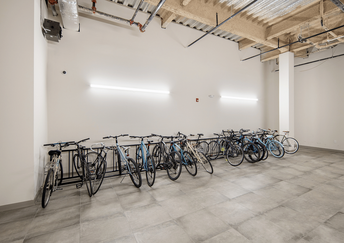 Secure indoor bicycle parking area with multiple bikes in a modern apartment complex.